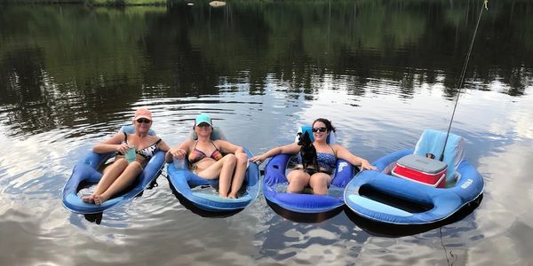 Three women relaxing on inflatable floats in a calm lake.