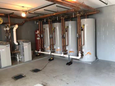A mechanical room with water heaters and copper piping.