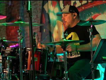 Drummer passionately playing on stage during a live performance.