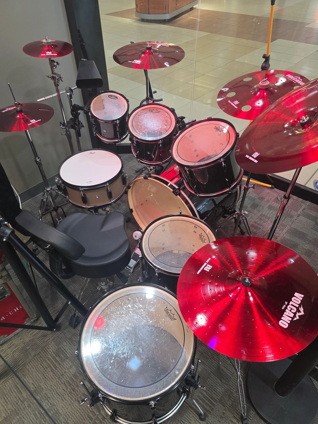 A detailed drum set with red cymbals in a room.
