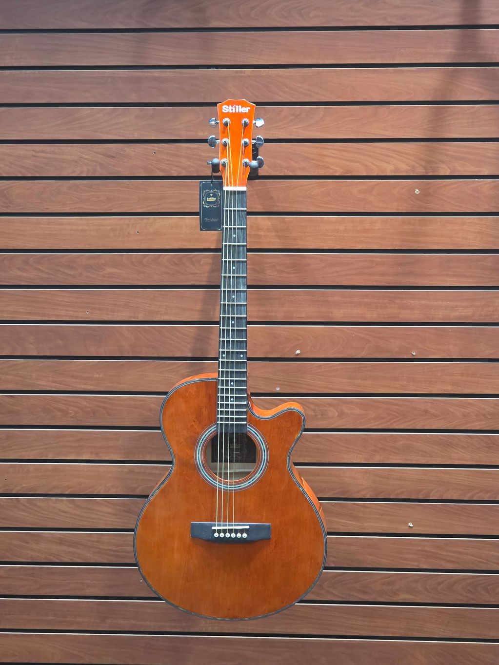 Acoustic guitar hanging on a wooden wall.