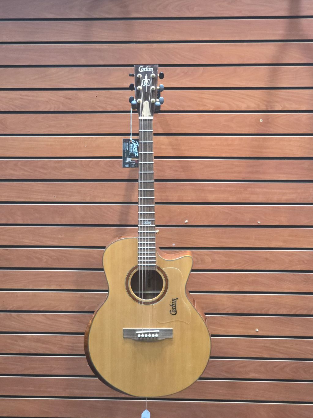 Acoustic guitar hanging on wooden wall.