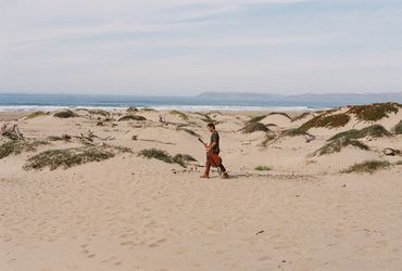 Man with guitar walks through sand dunes