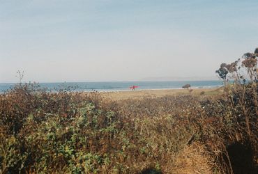 Man with surfboard walking across beach