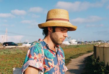 Man in colorful shirt and straw hat looking down