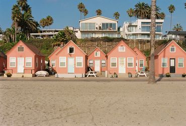 Small pink bungalows lined up on the beach.