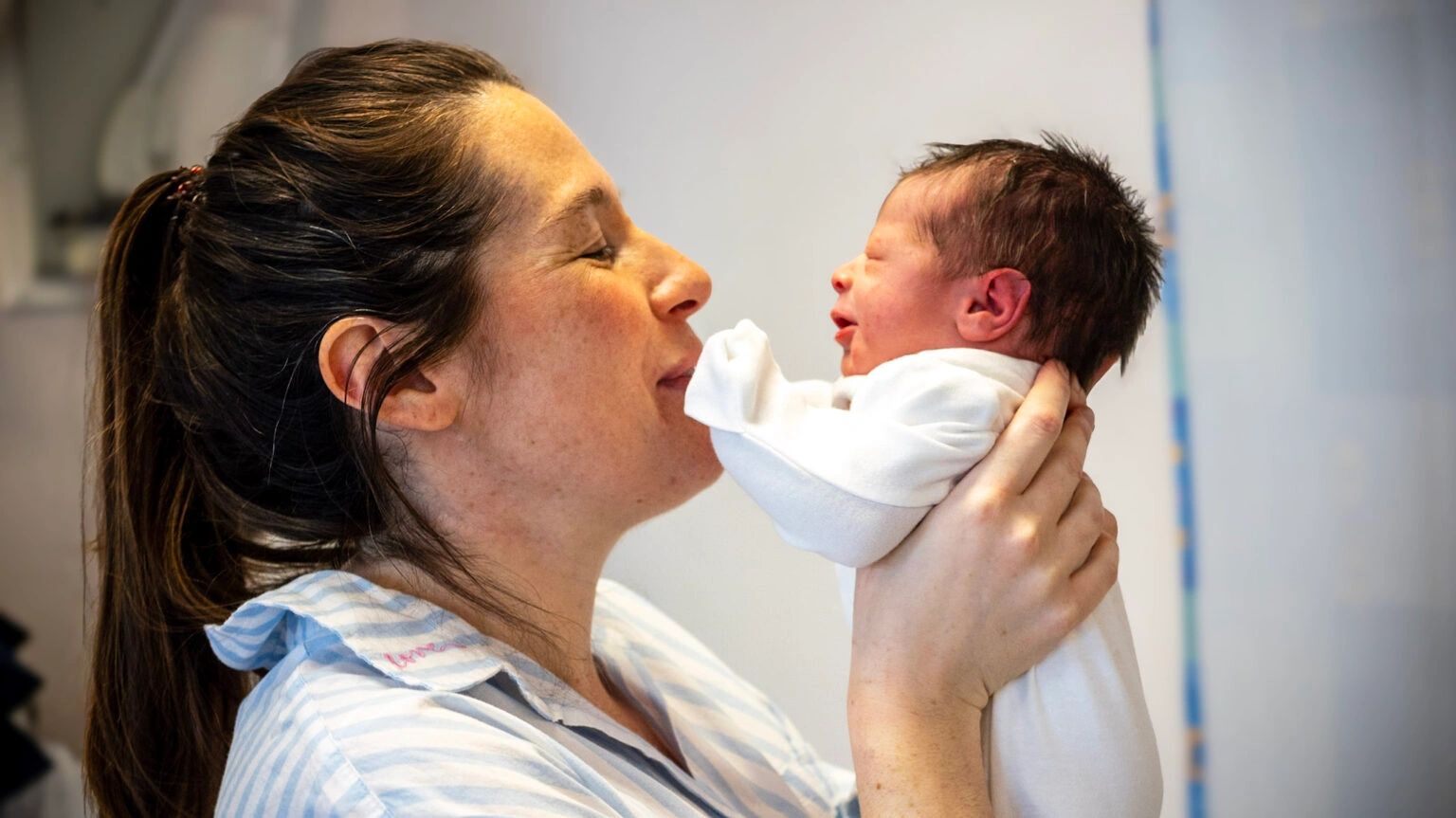 Mother lovingly holds and gazes at her newborn baby.