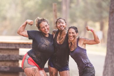 Group of girls smiling covered in mud