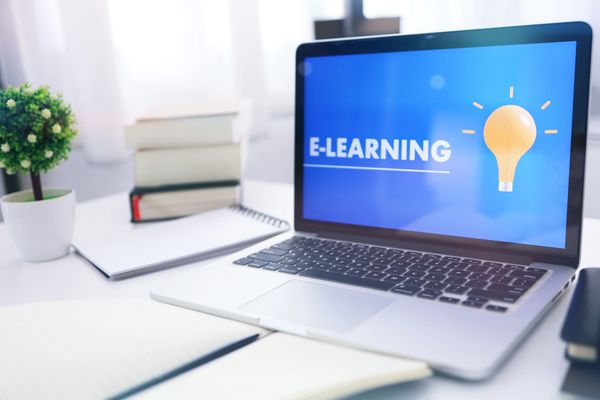 Image of a computer screen with the words E-learning on it and some books.