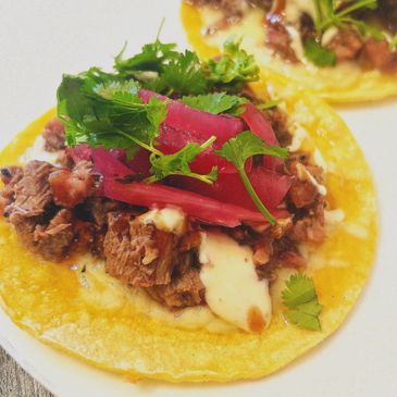 Smoked brisket tacos with pickled red onion, cilantro, crema, and honey chipotle BBQ sauce.