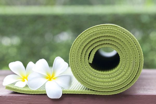 A rolled green yoga mat with white flowers.