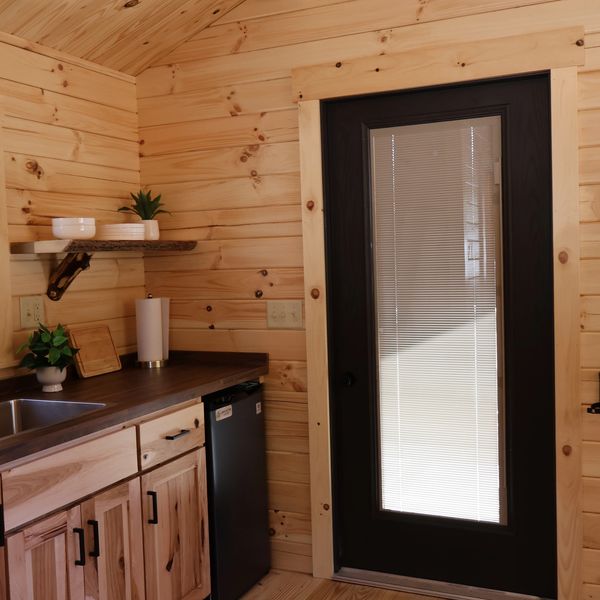 Cozy wooden kitchen corner with a black door featuring blinds.