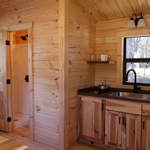 Cozy wooden cabin interior with kitchenette and shower.