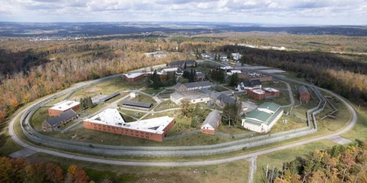 Aerial view of a large prison complex surrounded by fencing and forest.