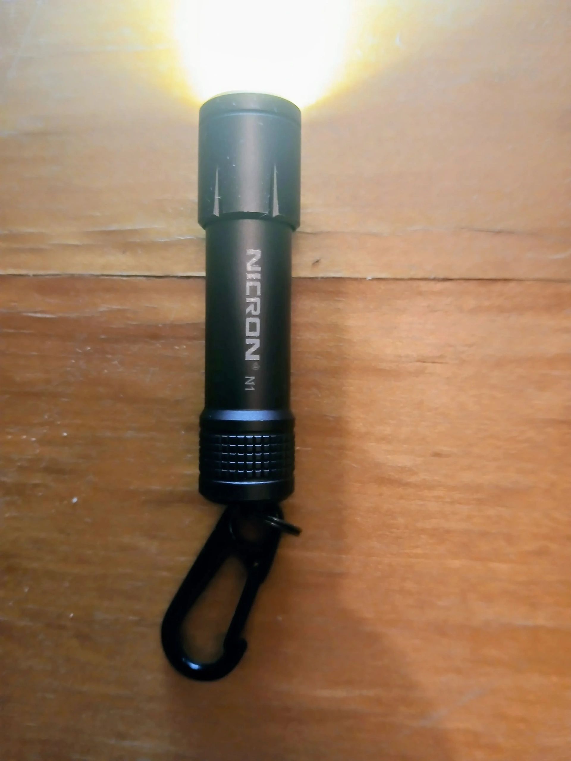 Compact flashlight glowing on wood surface