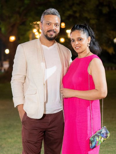 A couple posing outdoors at night with lights in the background.