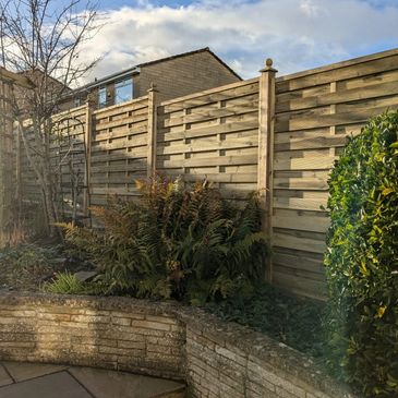 Panel fence installed on inclining garden, with decorative finial finshings.