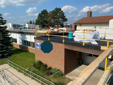 Coronation Public School building undergoing roof repairs with safety railings.