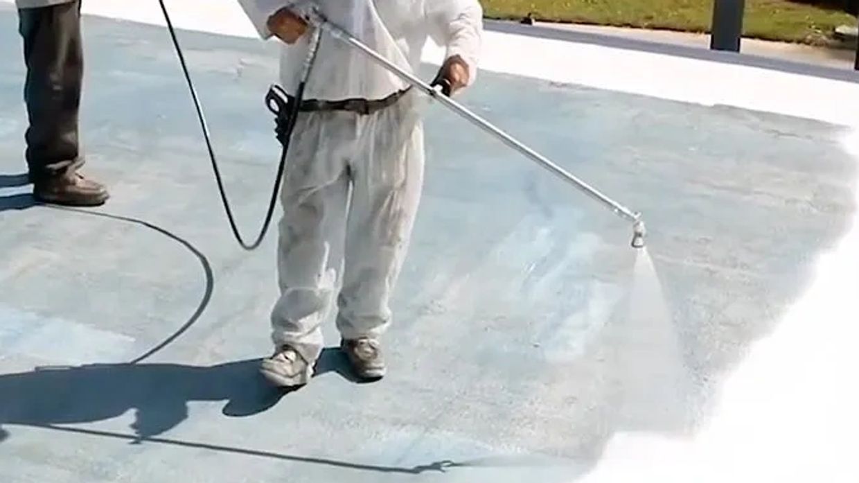 Person pressure washing a concrete surface outdoors.