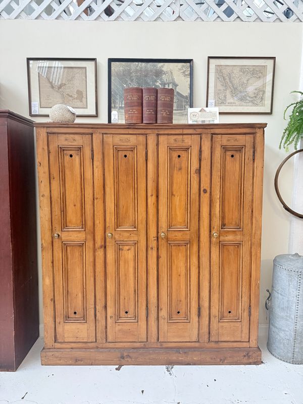 Vintage wooden cabinet with books and framed maps on top.