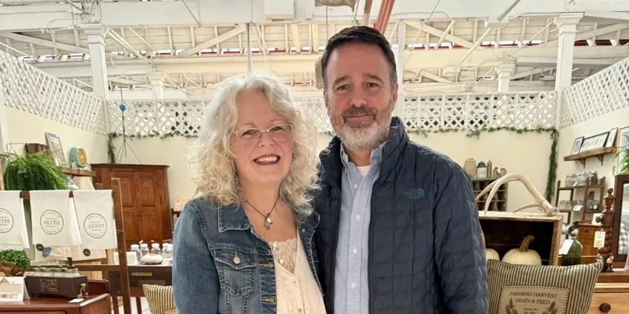 Smiling couple standing together in a rustic indoor market setting.