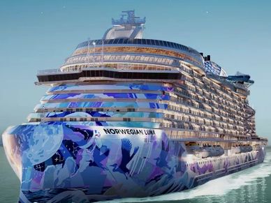 Large Norwegian Cruise Line ship with artistic hull design sailing on calm waters.