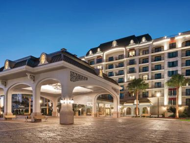 Elegant hotel entrance illuminated at dusk with a clear blue sky.