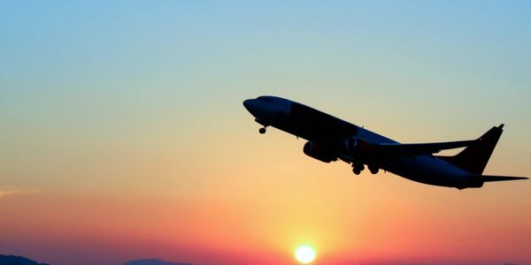 Silhouette of an airplane flying during a vibrant sunset.