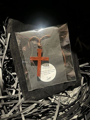 Wooden cross necklace in a black gift box with shredded paper.
