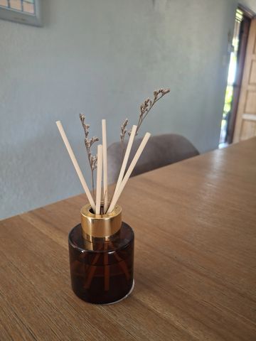 A reed diffuser with dried flowers on a wooden table.