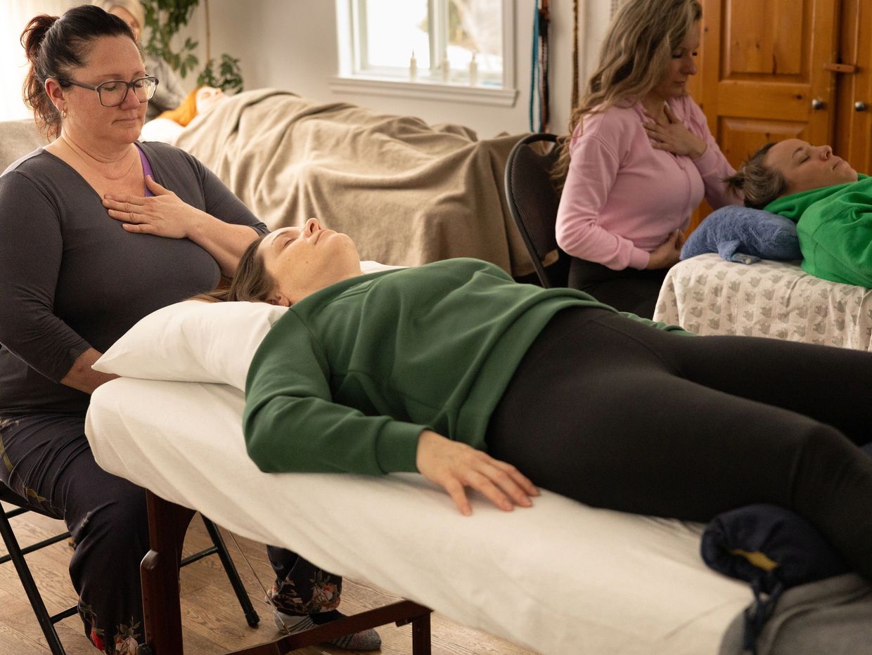 Two women practice breathing exercises with guides in a peaceful room.