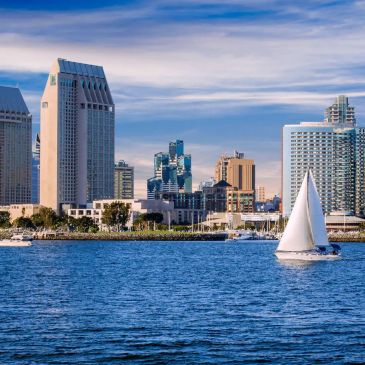Sailboat on water with city skyline background.