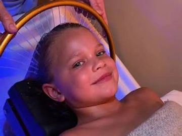 Smiling child resting with a golden hoop above their head.