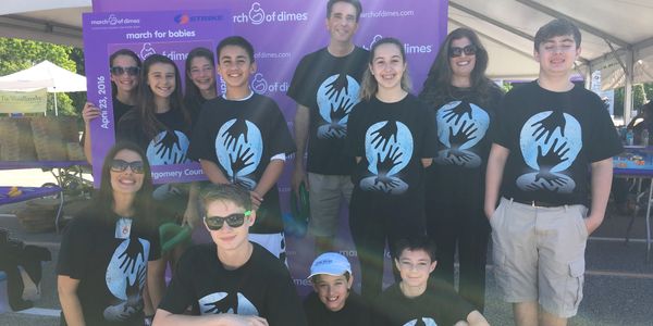 Group of people wearing matching black shirts at an outdoor event.