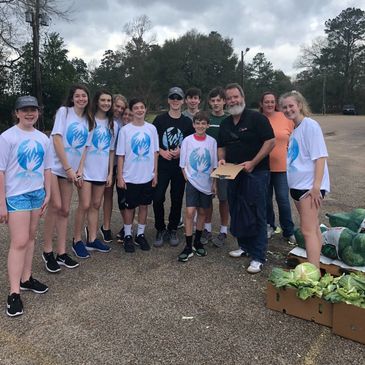 Group of people gathered outdoors with vegetables.