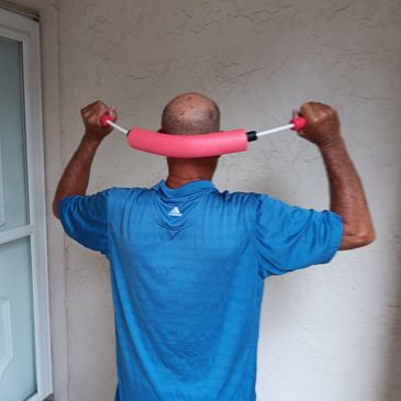Man using a pink neck massager on his neck indoors.