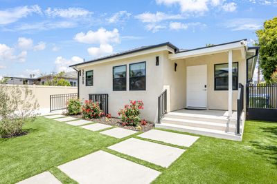 Modern single-story house with beige exterior and well-maintained lawn.