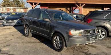 A dark-colored Volvo SUV parked in a lot on a sunny day.