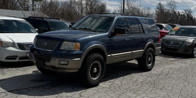 A dark blue Ford SUV parked in a lot among other cars.