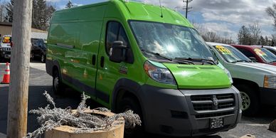 Bright green commercial van parked outdoors beside other vehicles.