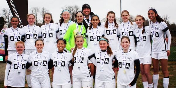Coach John Tait with girls youth soccer team after tournament, celebrating positive team culture.