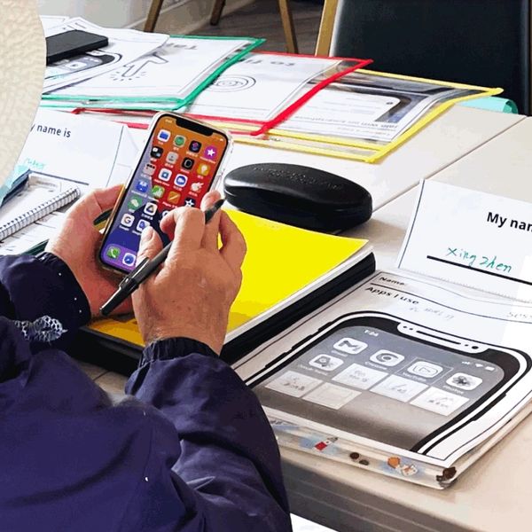 Person holding a smartphone and pen over a table with documents and folders.