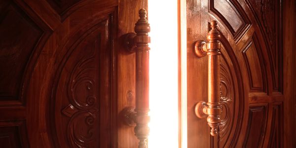 Wooden double doors partially open with bright light shining through, symbolizing hope and renewal