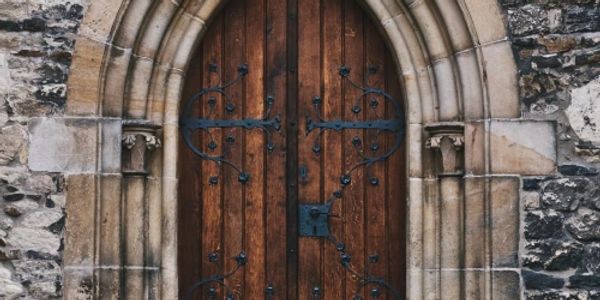 Arched wooden door set in carved stone, partially open symbolizing clarity and direction