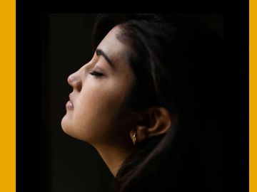Profile of a woman with closed eyes against a dark background.