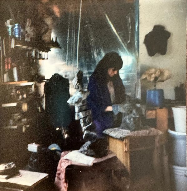 A woman working with clay in a dimly lit pottery studio.