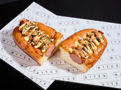 Two hot dogs with sauces and toppings on branded paper.