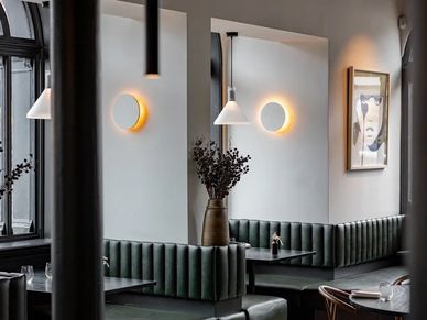 Modern dining area with green seating and illuminated wall lights.