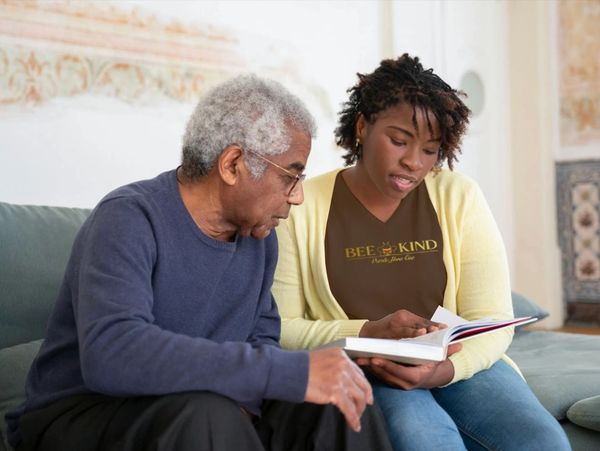 Home health aide reading to elderly client