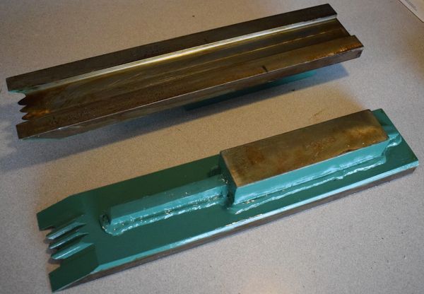 Two metal industrial parts with green-painted bases on a gray surface.